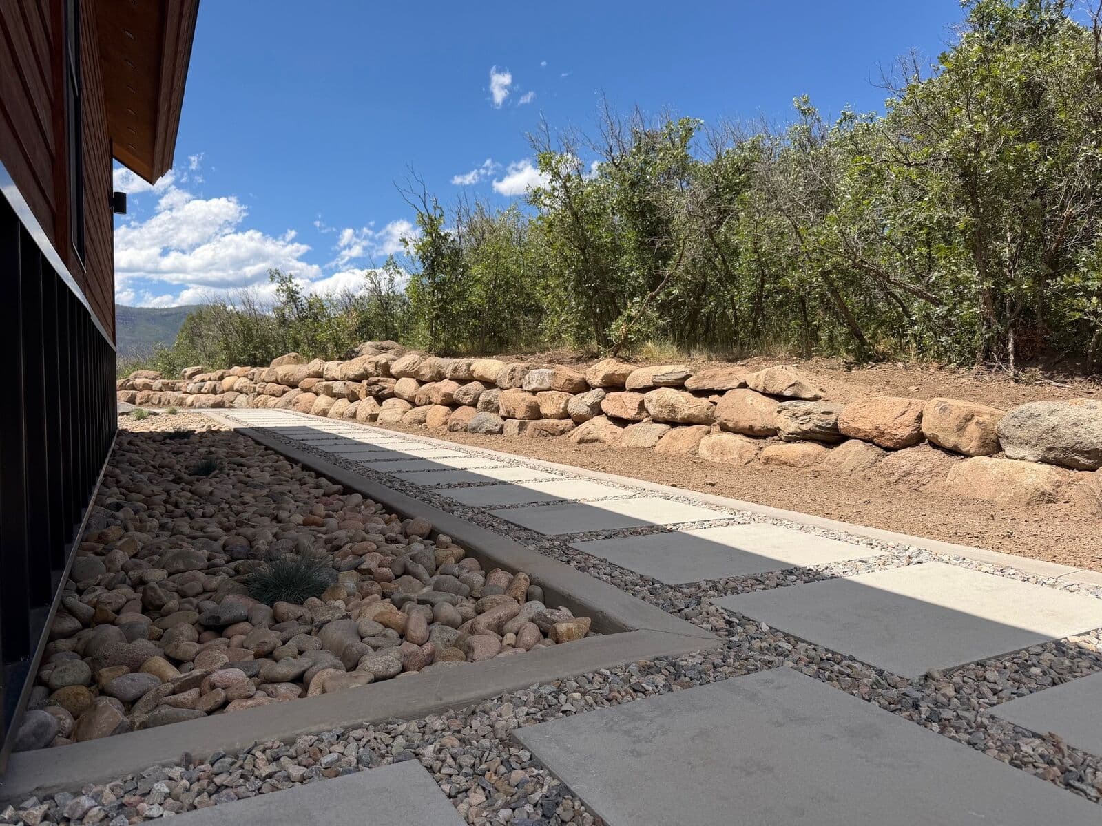 Boulder retaining wall and concrete paver walkway beside a mountain home in Durango, Colorado by LandEx Earthworks