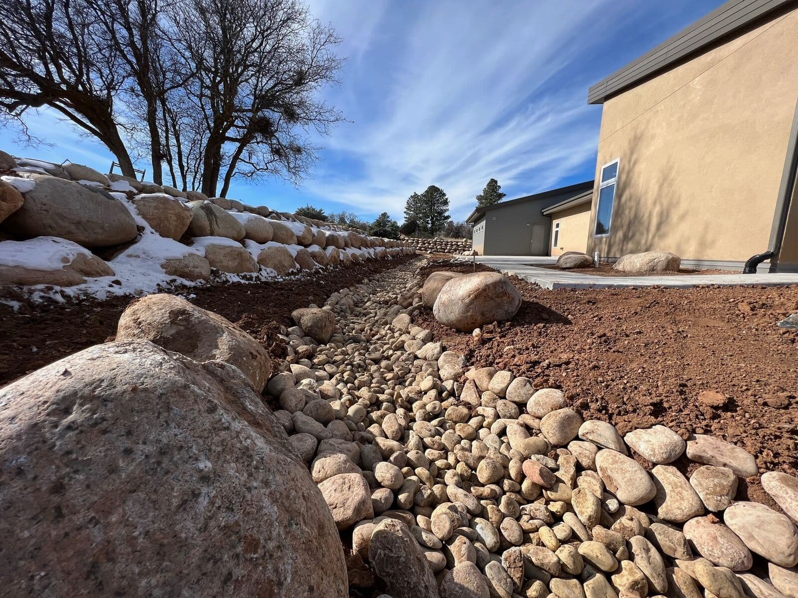 River rock drainage swale with boulders protecting a home in Durango